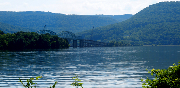 [Large body of water with a two-arched bridge passing over it. Rolling green hilltops backdrop the water.]